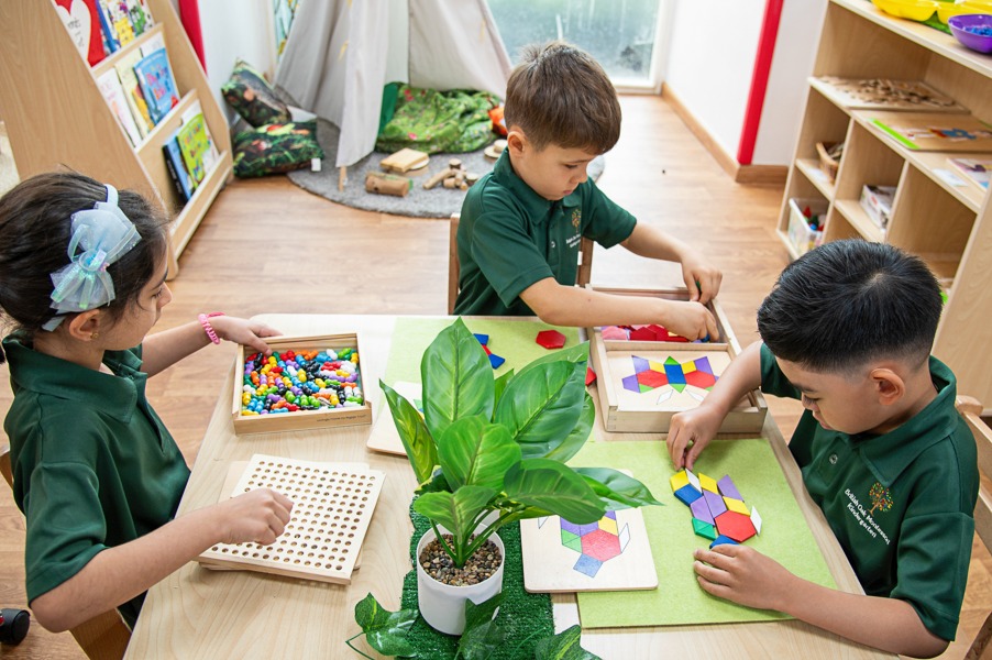 Children in British Oak green uniforms working with Montessori shape materials